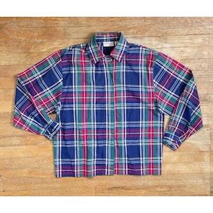 Può includere: Una camicia a maniche lunghe con bottoni a quadri blu, verdi, rossi e bianchi.
