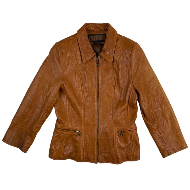 May include: A brown leather jacket with a zip fastening and a STUDIO label on the collar.
