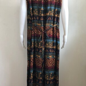May include: A long, sleeveless dress with a colorful geometric pattern in shades of brown, blue, green, and red. The dress has a tie at the waist.
