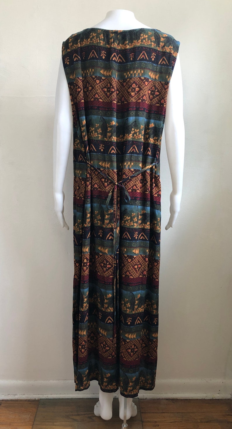 May include: A long, sleeveless dress with a colorful geometric pattern in shades of brown, blue, green, and red. The dress has a tie at the waist.