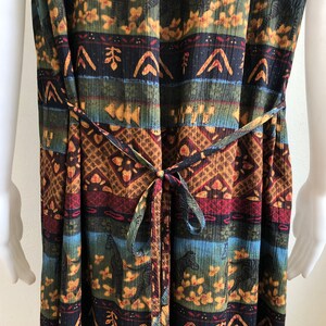 May include: A long, sleeveless dress with a colorful, tribal-inspired print featuring zebras and geometric patterns. The dress has a tie at the waist.