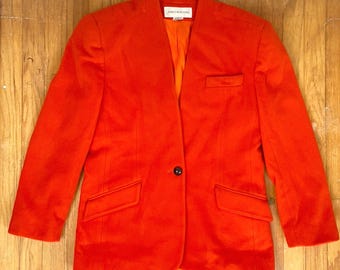 Könnte beinhalten: Ein leuchtend orangefarbener Blazer mit einem einzigen Knopfverschluss und zwei Taschen. Der Blazer trägt ein Etikett mit der Aufschrift "Jones New York".