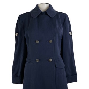 Pu&ograve; includere: Un cappotto blu scuro doppiopetto con collo e bottoni argentati. Il cappotto ha due tasche e strisce bianche sulle maniche.