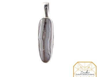 May include: A silver pendant featuring a gray and white banded agate stone. The stone is oval shaped and has a natural, organic pattern.