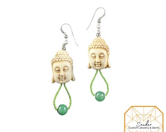 May include: A pair of silver earrings with a white Buddha head charm and a green jade bead on each earring.