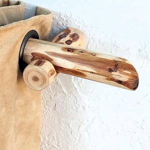 May include: A rustic wooden curtain rod with a natural finish, featuring a cylindrical design and a decorative end piece. The rod is paired with a tan fabric curtain, creating a warm, natural aesthetic. The rod is approximately 30 inches long.