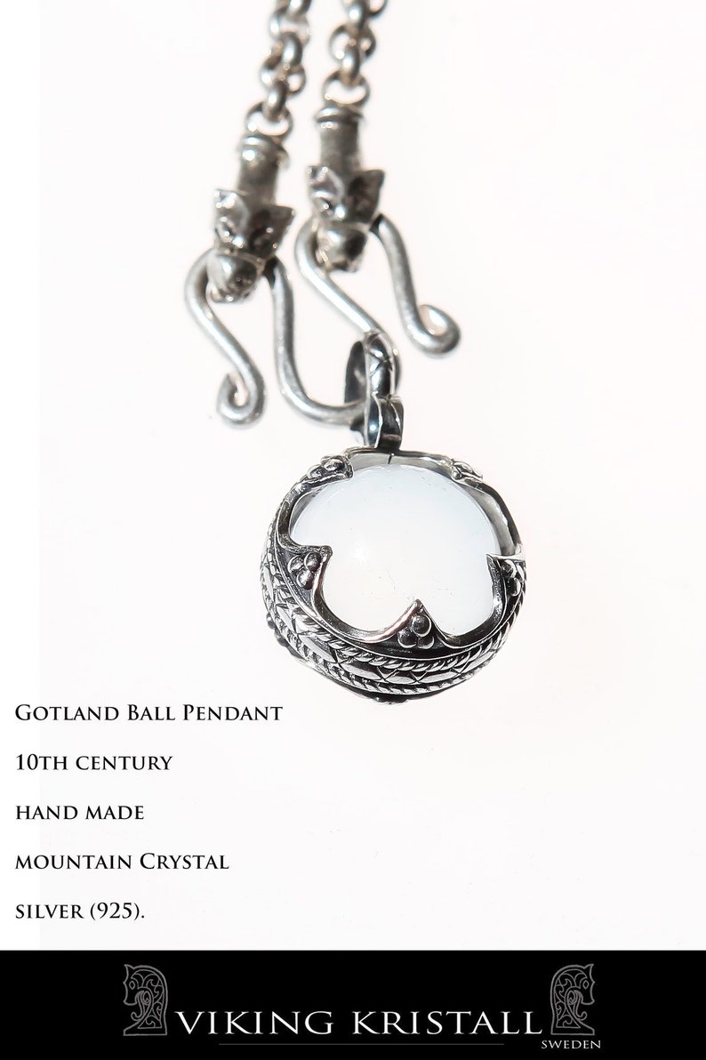 Puede incluir: Un colgante de bola de Gotland de plata con un cristal de roca blanco. El colgante est&aacute; en una cadena de plata con dos cierres de cabeza de drag&oacute;n. El colgante est&aacute; hecho a mano y data del siglo X. El texto "VIKING KRISTALL SUECIA" est&aacute; en la parte inferior de la imagen.