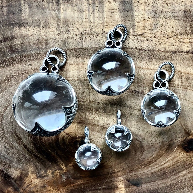 May include: Five silver pendants with clear crystal stones. Each pendant features a detailed silver design around the crystal.