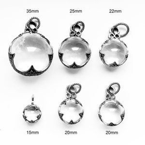 May include: Six silver pendants with clear glass stones, ranging in size from 15mm to 35mm. The pendants have a delicate floral design around the stone.