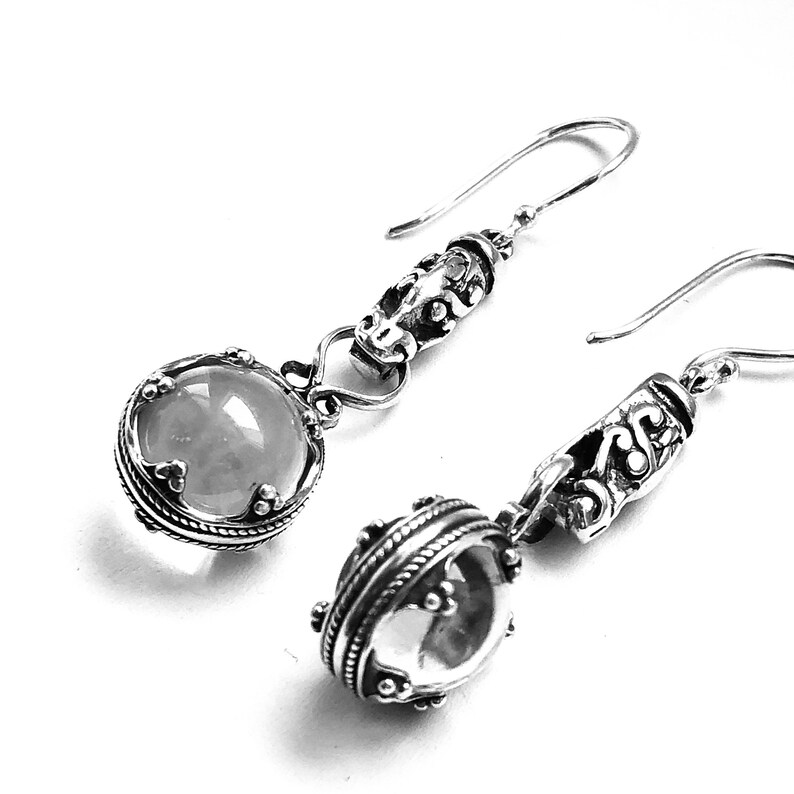 May include: A pair of silver earrings with clear round stones and intricate filigree designs.