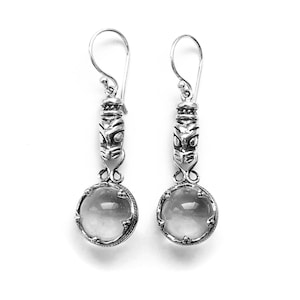 May include: Silver earrings with a clear glass bead and a silver tiki-style charm.