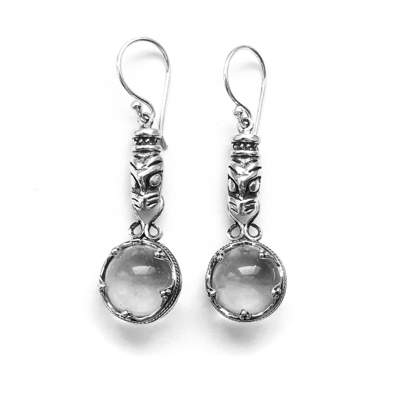 May include: Silver earrings with a clear glass bead and a silver tiki-style charm.