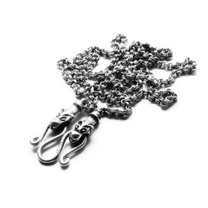 May include: A silver chain necklace with two dragon head clasps. The chain is made of small, linked rings.
