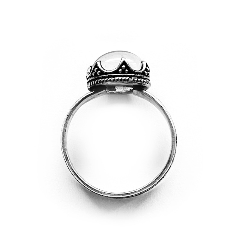 May include: A silver ring with a clear, round gemstone set in a crown-like setting.