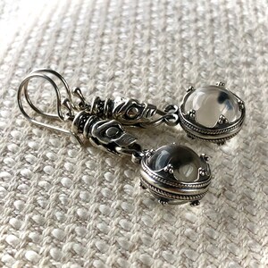 May include: Silver earrings with clear crystal stones and a detailed dragon design.