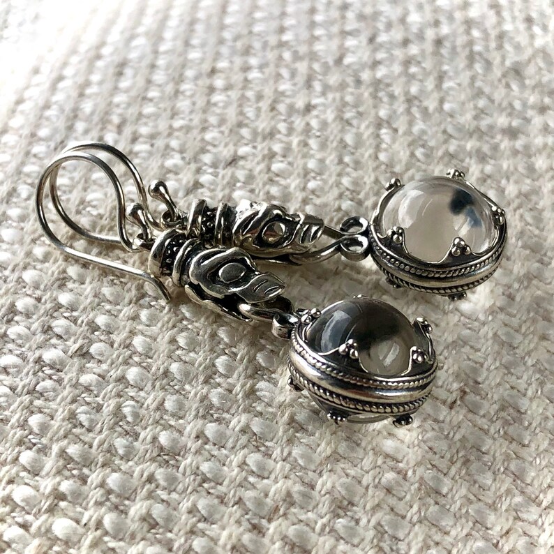 May include: Silver earrings with clear crystal stones and a detailed dragon design.