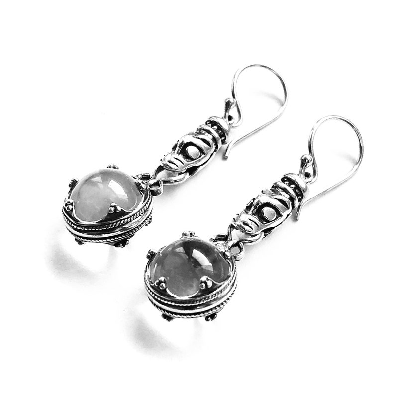 May include: A pair of silver earrings with a clear gemstone and intricate detailing. The earrings have a drop design and are perfect for adding a touch of elegance to any outfit.