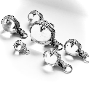 May include: Five silver pendants featuring clear glass orbs. Each pendant has an elaborate design and a loop for attaching to a chain.