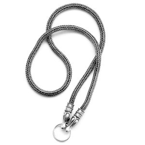 Op de afbeelding: Een zilveren ketting met een gevlochten ontwerp en een drakenkop sluiting. De sluiting heeft een ring.