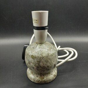 May include: A white ceramic lamp base with a green and brown marbled pattern. The lamp has a white cord and a white light socket with a black switch.