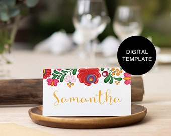 May include: A white place card with a colorful floral border and the name "Samantha" written in gold script.