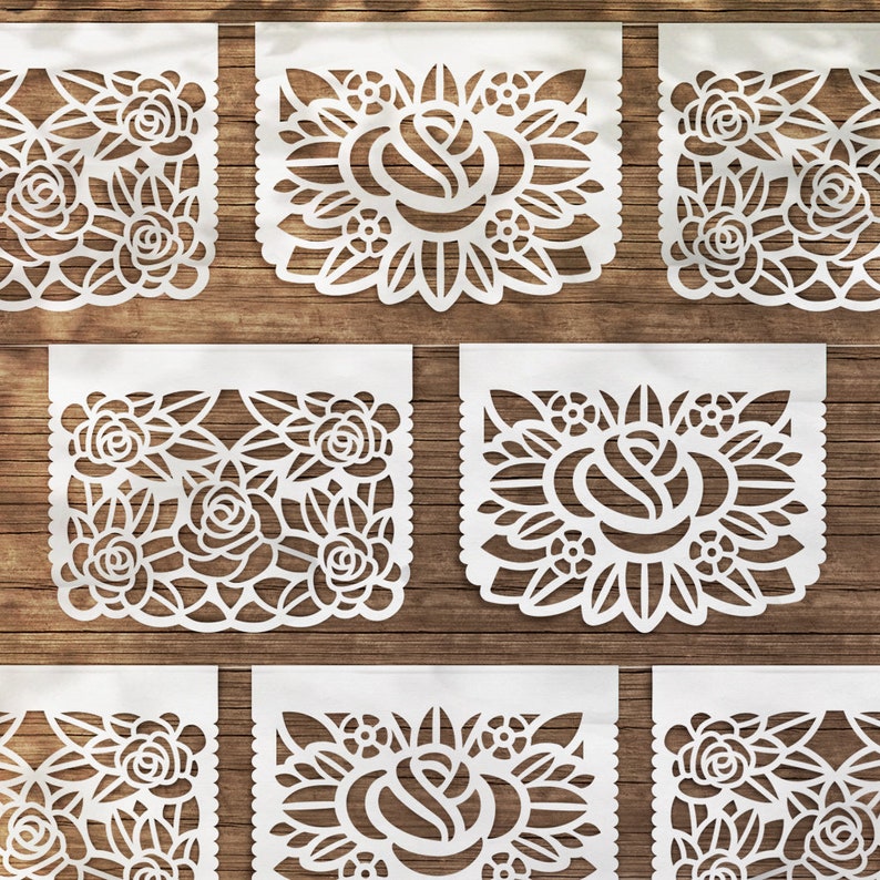 K&ouml;nnte beinhalten: Satz von acht wei&szlig;en Papierschnitten mit einem floralen Design. Jeder Schnitt zeigt eine Rose mit filigranen Details und einem gewellten Rand. Die Schnitte sind in einem Rastermuster auf einer Holzoberfl&auml;che angeordnet.