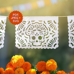 May include: White paper banner with a skull design, part of a Day of the Dead celebration. The banner has a scalloped edge and is strung with other banners. The image also includes orange marigold flowers and the text "PDF, JPEG + SVG".