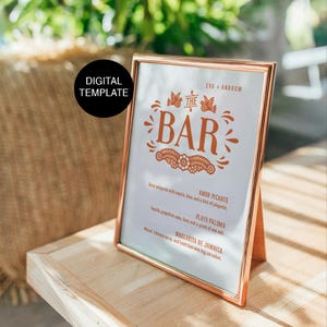 May include: A gold-framed sign with the text "The Bar" in a decorative font. The sign lists three cocktail options: Amor Picante, Playa Paloma, and Margarita de Jamaica.
