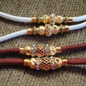 May include: Two dog leashes, one white and one burgundy, with gold and rhinestone accents.