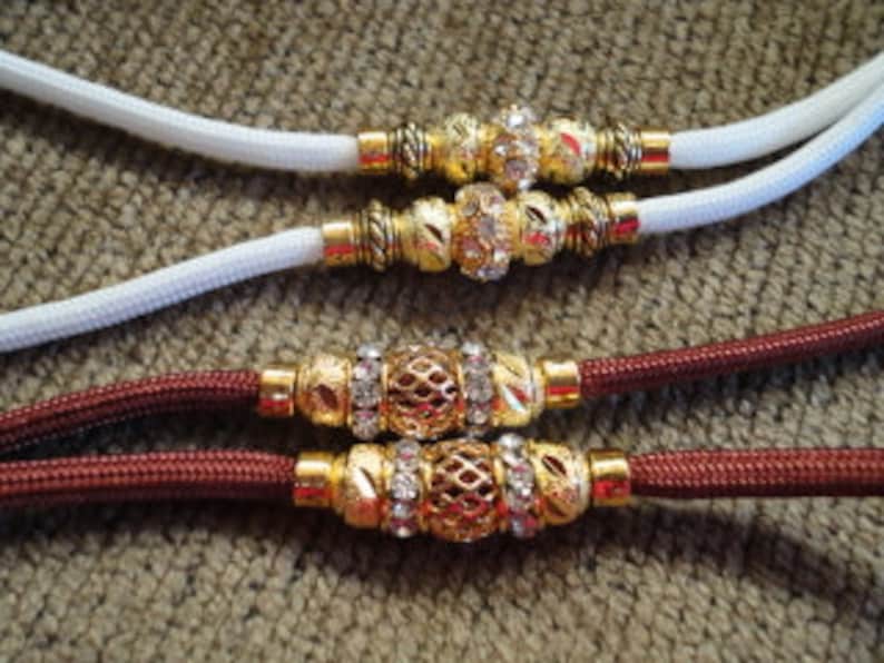 May include: Two dog leashes, one white and one burgundy, with gold and rhinestone accents.