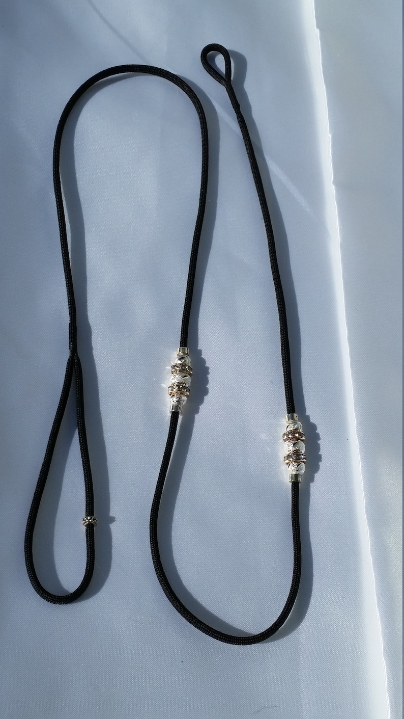 May include: A black paracord leash with silver and gold beads. The leash has a loop at one end and a slip knot at the other.