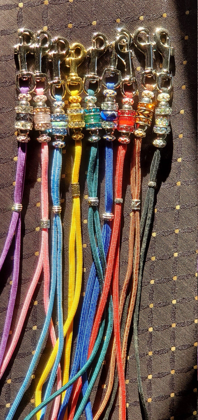 May include: A set of ten colorful, braided cords with silver clasps and crystal beads. Each cord has a different color and crystal bead design.