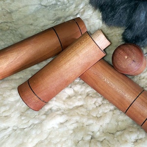 May include: Three wooden dowels with black lines around the center. The dowels are on a white fluffy surface.