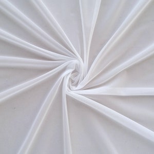 Op de afbeelding: Witte, doorschijnende stof met een zachte, delicate textuur. De stof is in het midden samengebracht, waardoor een draaiend patroon ontstaat.