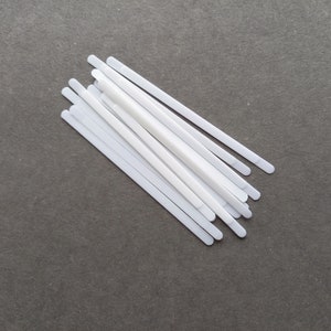 Op de afbeelding: Een bundel witte plastic strips, waarschijnlijk voor gebruik in knutselwerk of doe-het-zelfprojecten.