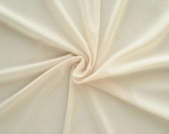 May include: A close-up of a smooth, off-white fabric with soft folds and wrinkles.