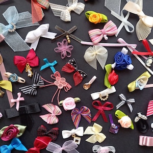 May include: Assortment of colorful handmade fabric bows and ribbons. The bows are made with various materials, including satin, velvet, and lace. The ribbons are in a variety of colors, including red, blue, green, pink, and yellow.