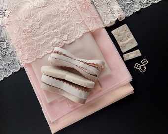 May include: A set of pink fabric pieces for sewing a bra, including lace, mesh, and elastic. The fabric pieces are laid out on a black surface, along with bra clasps and hardware.