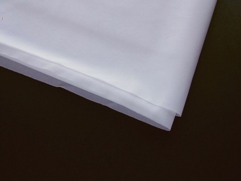 May include: White sheer fabric with a soft, delicate texture. The fabric is folded over on itself, creating a smooth, even edge.