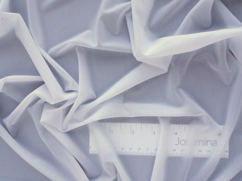 May include: White sheer fabric with a ruler showing 16 inches. The ruler has the word "Jolmina" printed on it.
