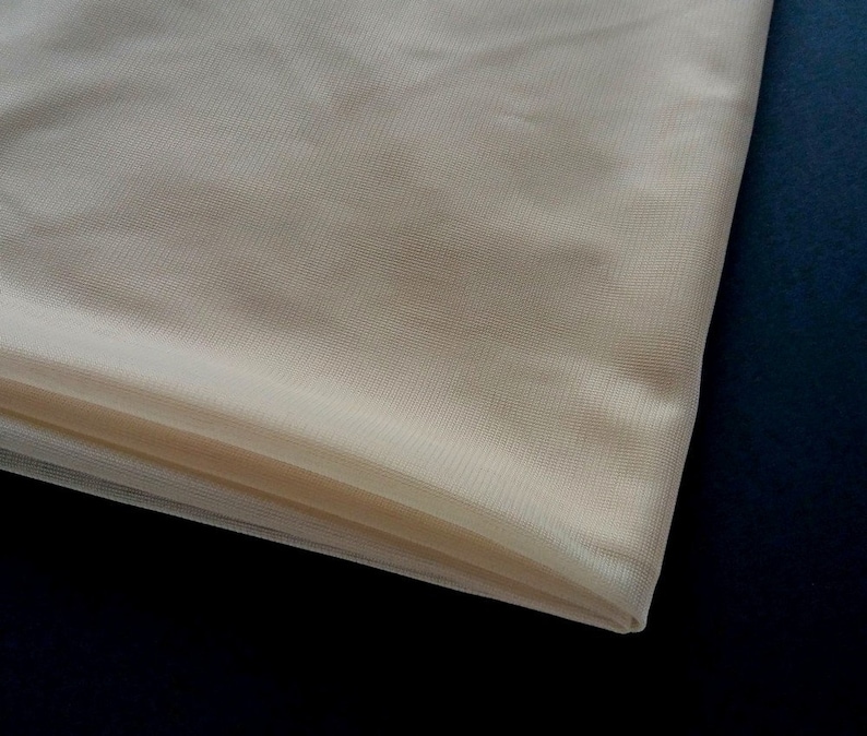 Puede incluir: Un trozo de tul transparente de color blanco roto. La tela est&aacute; doblada y tiene una textura suave y delicada.