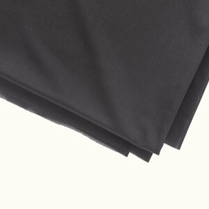 May include: Black fabric folded in thirds, showing the smooth texture of the material.