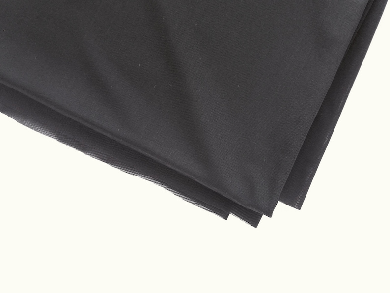 May include: Black fabric folded in thirds, showing the smooth texture of the material.