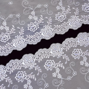 May include: White lace trim with a scalloped edge and floral embroidery. The lace is delicate and intricate, with a subtle shimmer.