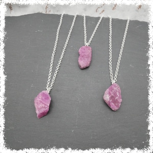 Puede incluir: Tres collares de plata con colgantes de cristal rosa. Los cristales son ásperos y tienen un aspecto natural y bruto.