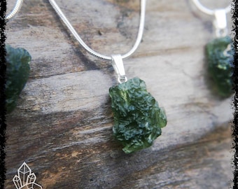 May include: A silver chain necklace with a green, rough, and textured pendant. The pendant is a natural stone, possibly moldavite.