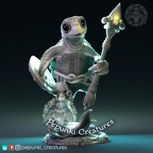 Könnte beinhalten: Detaillierte Figur einer schildkrötenartigen Kreatur, die einen Stab mit leuchtender Spitze hält. Die Figur ist hellgrau mit aufwendigen Details, darunter ein Seil um die Taille und ein Sockel mit einem Delfin. Der Text "Pepunki Creatures" ist sichtbar.