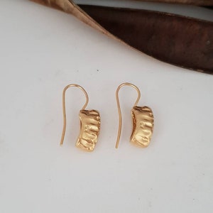 May include: A pair of gold hoop earrings with a textured surface. The earrings have a simple hook closure.