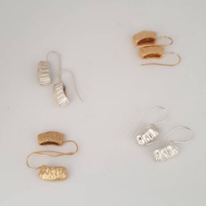 May include: Four pairs of earrings, two pairs are gold and two pairs are silver. The earrings are all textured and have a curved shape.
