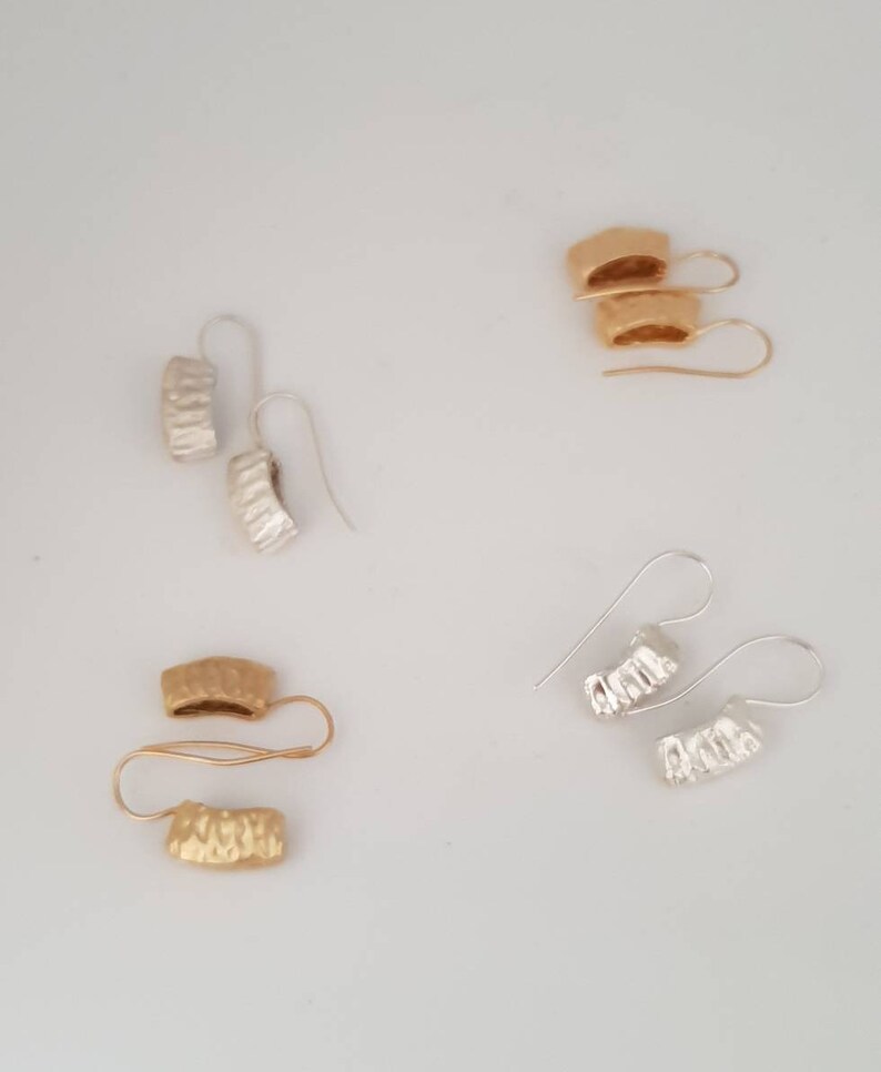 May include: Four pairs of earrings, two pairs are gold and two pairs are silver. The earrings are all textured and have a curved shape.